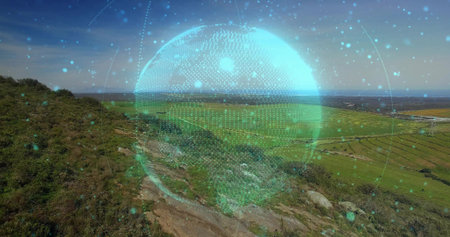 Displaying digital holographic globe floating above hillside, near rocky footpath toward farm plots. Futuristic, technology, innovation, connectivity, landscape, neural, digitalの写真素材