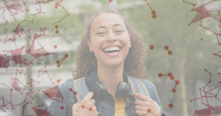 Smiling woman holding backpack walking on path in denim jacket, headphones under network overlay....