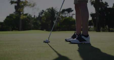 Standing golfer in shorts and golf shoes on putting green with putter and ball, copy space. Athletics, recreational, outdoor, leisure, bright, professional, athleticの写真素材