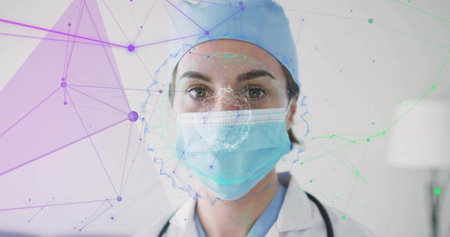 Standing doctor wearing scrub cap and mask in clinical office, with stethoscope and mesh overlay. Medical, telemedicine, digital, healthcare, diagnostic, professional, technologyの写真素材