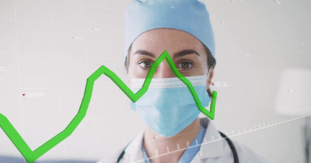 Doctor wearing cap and mask analyzing data in clinic, with stethoscope, green line graph overlay. Medical, healthcare, data, analysis, clinical, professional, diagnosticsの写真素材