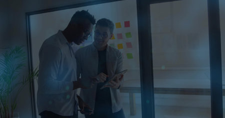 Reviewing tablet coworkers in business casual holding phone in office, with colorful sticky notes....