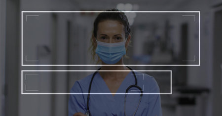 Standing nurse wearing blue scrubs and surgical mask in hospital corridor, with stethoscope visible. Medical, healthcare, clinical, professional, hospital, diagnostic, caregiverの写真素材
