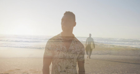 Standing man wearing palm shirt gazing at sea at sunset, surfer carrying surfboard walking shore. Coastline, sunset, reflection, ocean, adventure, leisure, lifestyleの写真素材