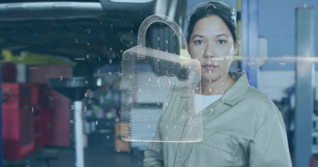 Technician examining 3D padlock interface in workshop, wearing coveralls and goggles, copy space. Automotive, workshop, security, technology, industry, repair, innovationの写真素材