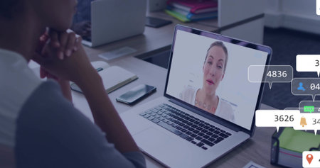 Mature African American man leaning toward laptop at office, with smartphone, overlays, copy space. Professional, teamwork, collaboration, modern, workplace, digital, communicationの写真素材