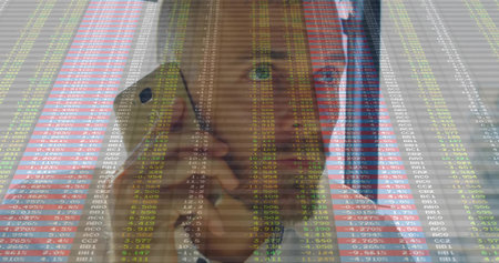Conducting smartphone call mid adult male professional in office, with stock market data overlay. Corporate, finance, technology, data visualization, modern, professional, analyticalの写真素材
