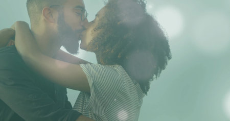 Embracing couple kissing in photographic studio, with eyeglasses and black shirt and striped top. Romance, intimacy, connection, affection, diversity, emotional, modernの写真素材