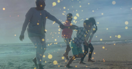 Holding hands grandparents with grandkids walking along beach under golden light and gentle waves. Family, beach, shoreline, sunset, togetherness, leisure, harmonyの写真素材
