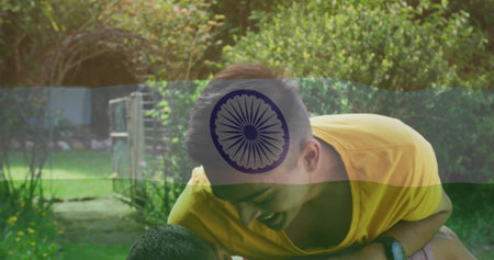 Man in yellow t-shirt carrying friend on back in backyard, with metal gate and trimmed hedges. Friendship, outdoor, leisure, vibrant, happiness, nature, casualの写真素材