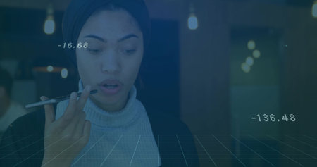 Issuing voice command using smartphone, woman standing in modern office with floating data and grid....
