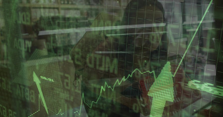 Asian financial analyst wearing shirt analyzing stock graphs on laptop at desk, binders behind. Corporate, investment, data, technology, professional, modern, businessの写真素材