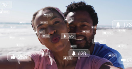 Taking selfie couple in pink top, blue shirt on sunny beach, with phone, social media notifications....
