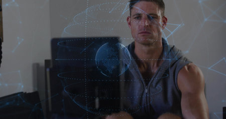 Interacting man in hoodie using holographic network globe in office, with computer monitors. Futuristic, innovation, connectivity, technology, digital, workspace, successの写真素材