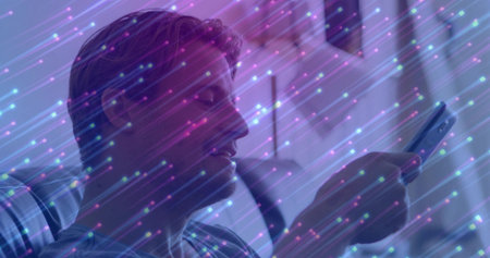 Holding smartphone man in striped tee sitting in lounge chair with cushion at home, glowing streaks. Technology, modern, digital, innovation, relaxation, futuristic, interiorの写真素材