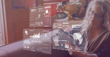 Woman wearing cardigan holding tablet with holographic graphs on sofa at home, copy space. Technology, innovation, professional, modern, digital, interior, insightfulの写真素材