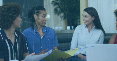 Reviewing papers on coffee table, colleagues in office lounge using laptop with folder, ceramic mug. Collaboration, teamwork, corporate, interior, modern, business, discussionの写真素材