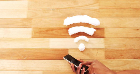 Tapping smartphone touchscreen with adult male hand on wooden tabletop, with foam Wi-Fi symbol. Technology, connectivity, communication, digital, modern, networking, innovationの写真素材