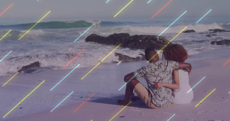 Sitting couple wearing floral shirt and sundress on beach, waves crashing on rocks, pastel overlay....