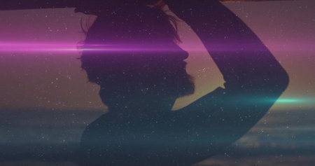 Standing silhouette bearded man raising arm at calm sea at dusk showing lens flares, starry grain....