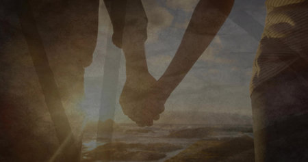 Holding hands couple strolling on coastal beach at sunset, capturing warm golden reflection. Romance, serenity, connection, tranquility, landscape, harmony, leisureの写真素材