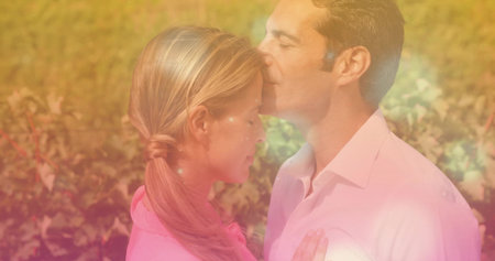 Embracing couple exchanging forehead kiss among sunlit grapevines during golden hour, warm light. Romance, intimacy, pastoral, tranquil, serenity, affection, rusticの写真素材