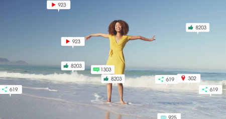 Standing woman wearing yellow dress holding arms outstretched on shoreline. Lifestyle, wellbeing, adventure, relaxation, summer, outdoor, serenityの写真素材