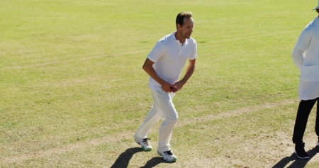 Running cricketer in uniform preparing to bowl on cricket pitch with red ball, markings, copy space....