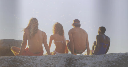 Basking group of friends soaking up warm sunlight on coastal rock outcrop, swimwear and bucket hat. Scenic, leisure, outdoor, casual, adventure, nature, relaxationの写真素材
