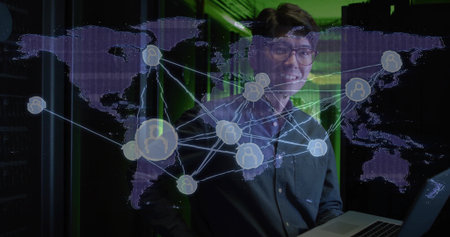 Standing IT professional in dark shirt holding laptop in green server room, with world map overlay....