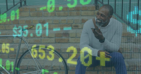 Sitting man speaking into smartphone on outdoor brick steps by bicycle with financial data overlay. Urban, technology, communication, casual, modern, leisure, progressionの写真素材