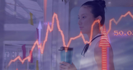 Standing Asian woman holding mug, viewing red charts over sticky notes in office hall, copy space....