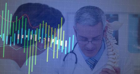 Senior doctor wearing stethoscope explaining spine model in clinic. Medical, healthcare,...