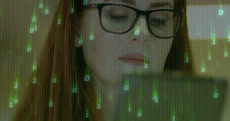Gazing female developer wearing eyeglasses analyzing code on laptop in study, with binary overlay. Technology, innovation, programming, cybersecurity, digital, concentration, workspaceの写真素材