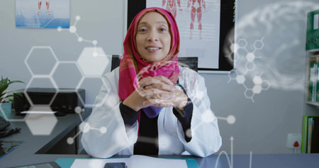Consulting female physician wearing headscarf and lab coat at clinic, with stethoscope, tablet. Medical, healthcare, telemedicine, digital, professional, innovation, clinicalの写真素材