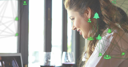 Typing woman in white blouse on laptop at cafe table, wine and network icons, copy space....