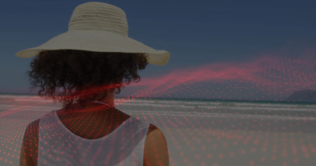 Standing woman wearing straw hat, sleeveless top at sandy shore by ocean, with red wave overlay. Coastal, leisure, tranquility, minimalism, nature, digital art, adventureの写真素材
