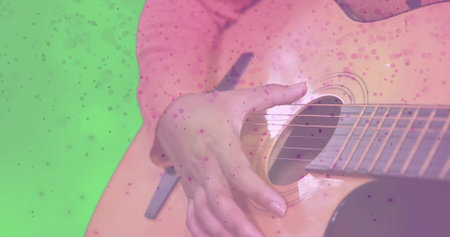 Strumming woman in pink dotted shirt in studio, with acoustic guitar and green chroma key backdrop. Musician, performance, entertainment, folk, melodic, art, vibrantの写真素材