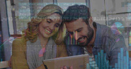 Smiling casually dressed couple leaning over tablet in bright lounge, with financial data overlay. Collaboration, technology, modern, communication, outdoor, positivity, lifestyleの写真素材