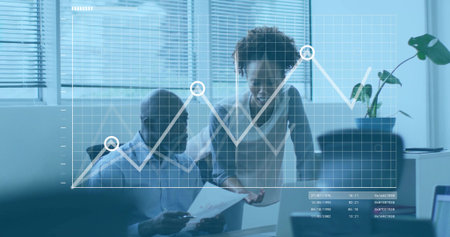 Collaborating two coworkers in office attire discussing report at desk, with line graph overlay....