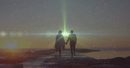 Walking couple strolling hand in hand along narrow stone pier over calm water, bright horizon light....