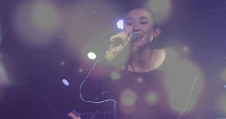Singer performing on stage in black top with microphone, colored spotlights and haze bokeh. Performance, concert, music, entertainment, atmosphere, artistic, stagecraftの写真素材
