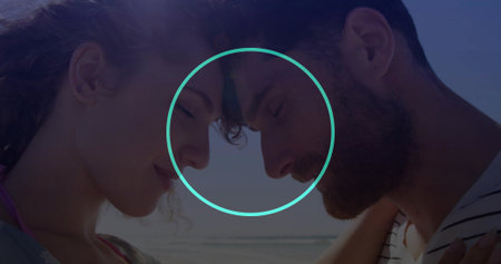 Couple touching foreheads in swim top and striped shirt at sandy shoreline, with glowing outline....