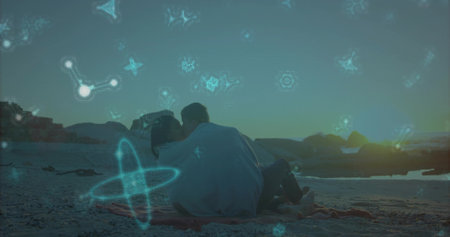 Sitting couple wrapped in gray blanket on sandy shore at dusk, with striped throw neon-blue symbols....