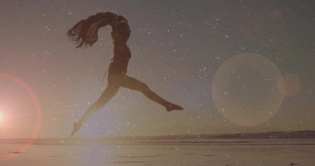 Silhouette dancer in flowing dress dancing in water at sunset, with trailing fabric and lens flare. Silhouette, movement, elegance, serenity, inspiration, nature, artistryの写真素材