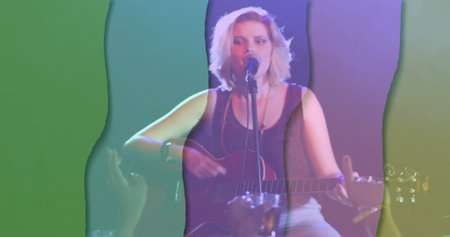 Strumming female musician singing into microphone on club stage, with guitar and colored lights....