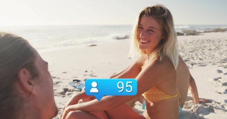 Smiling woman wearing yellow bikini sitting on beach, with copy space. Beach, summer, vacation,...