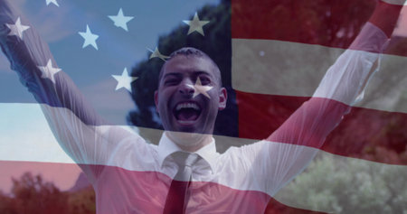 Raising arms white man wearing dress shirt and tie in park, with translucent American flag overlay. Celebration, patriotism, victory, outdoor, freedom, triumph, successの写真素材