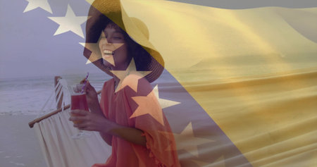 Black woman in straw hat relaxing on beach hammock with cocktail and umbrella. Tropical, leisure, vacation, bliss, outdoor, serenity, glamourの写真素材
