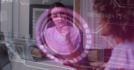 Holding pen mid-adult consultant in gray blouse examining laptop at office table, with HUD overlay. Collaboration, technology, innovation, business, modern, professional, productivityの写真素材